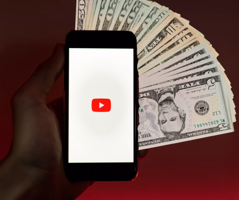 YouTube app on phone with cash representing making money on YouTube without showing your face